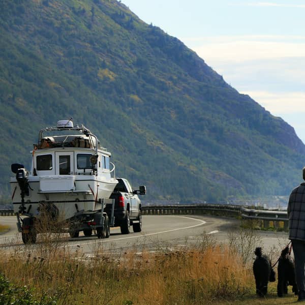 Pickup towing a fishing boat along a coastal mountain road