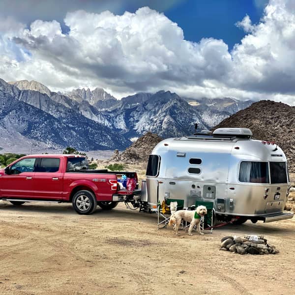 Red Ford F-150 hitched to a silver travel trailer at a desert campsite
